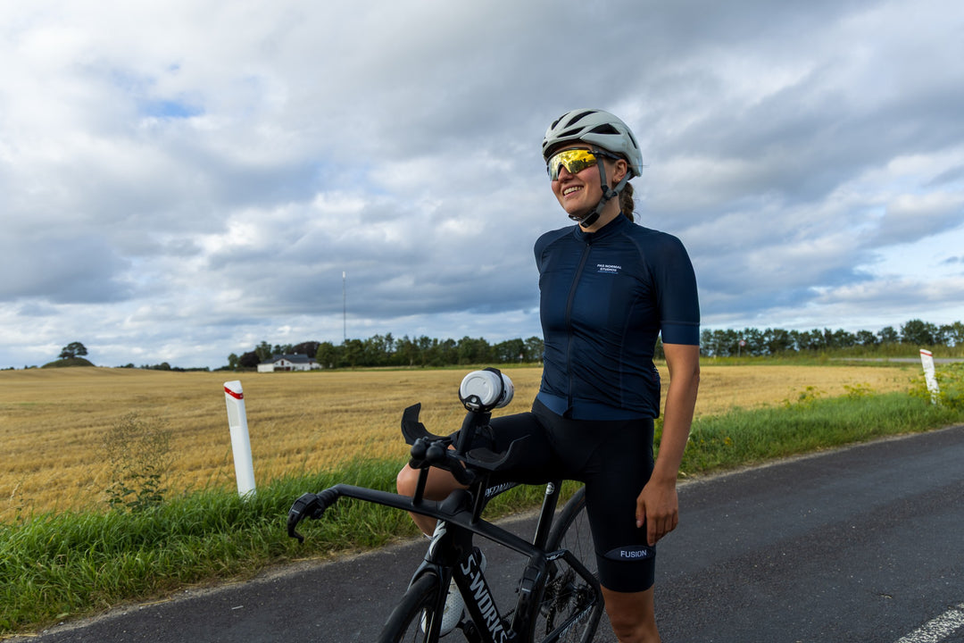 Rider standing with a Specialized S-Works TT bike on a country road, an AeroGain BTA bottle mounted between the extensions