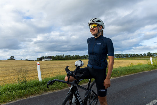 Rider standing with a Specialized S-Works TT bike on a country road, an AeroGain BTA bottle mounted between the extensions